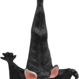 May include: A black hanging bat ornament with outstretched wings, pink inner ears, red eyes, and an open mouth showing white teeth. The bat is suspended by a thin gold string attached to a metal loop at the top of its head, hanging in a vertical position.