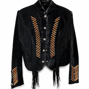 May include: A black suede jacket featuring long fringe detailing across the chest and sleeves. The front is adorned with vertical rows of light brown wooden beads and silver-toned metal concho buttons running down the center closure.