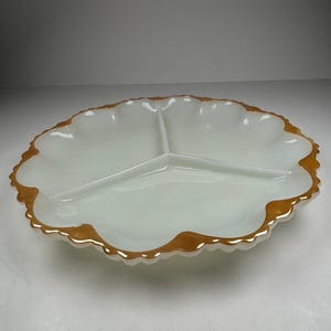 Peut inclure: Plat de service en verre blanc à trois compartiments, avec un bord festonné et une bordure dorée. Le plat a une forme de trèfle et est conçu pour servir des amuse-gueules ou des collations. Les sections intérieures sont divisées par des séparateurs en verre surélevés.