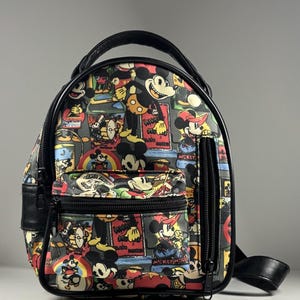 Puede incluir: Una mochila peque&ntilde;a con un estampado colorido de Mickey Mouse en varias poses y atuendos. La bolsa tiene bordes negros, un asa superior, un bolsillo frontal con cremallera y un bolsillo lateral vertical con cremallera en color negro.