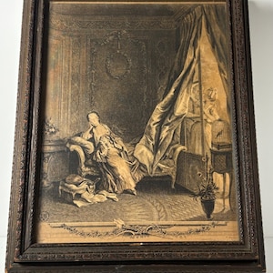 May include: An antique framed print depicting a woman in a room with a draped bed, a birdcage, and a potted plant. The print is in sepia tones and is set within a dark brown, ornate wooden frame. The image evokes a sense of historical elegance.