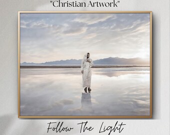 Könnte beinhalten: Ein Vintage-Kunstdruck mit einer Person in einem weißen Gewand, die in einem Gewässer mit Bergen im Hintergrund steht. Der Text "Follow The Light" steht unter dem Bild.