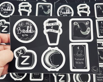 May include: A set of black and white stickers with various designs, including a coffin with the text "Let me sleep", a crescent moon, a witch's hat, and the text "Natural Witch".