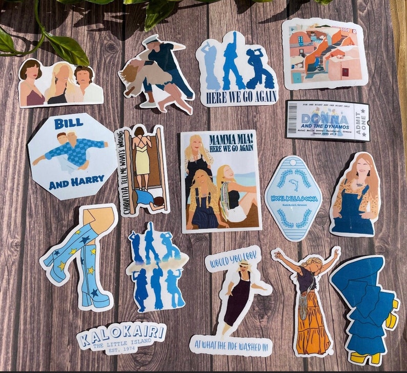 May include: A set of 14 stickers featuring illustrations from the Mamma Mia! movie. The stickers are on a wooden background. The stickers feature characters from the movie, including Donna, Sophie, and the other Dynamos. The stickers also feature text from the movie, such as "Here We Go Again" and "Would You Love."