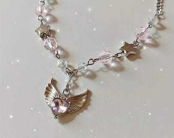 May include: A silver necklace with pink and clear beads, silver stars, and a silver charm with a pink heart and wings.