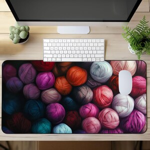 May include: A colorful mousepad featuring a close-up of a variety of yarn balls in shades of red, pink, purple, blue, green, and brown. The yarn balls are arranged in a random pattern, creating a visually appealing and textured design.