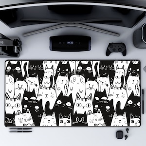 May include: Black and white mousepad with a pattern of cartoon cats. The cats are in various poses and have different expressions. The mousepad is rectangular and has a black border.