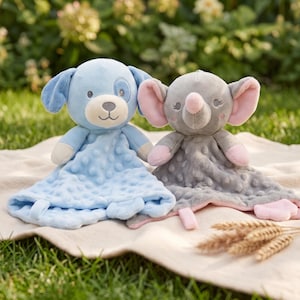 Könnte beinhalten: Zwei Kuscheltiere als Schmusetuch mit Tierköpfen. Eines ist ein hellblauer Hund mit einem genoppten Muster auf der Decke. Das andere ist ein grauer Elefant mit rosa Innenohren und einem passenden genoppten Muster auf der Deckenunterseite.