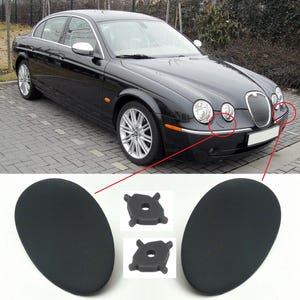 Op de afbeelding: Een zwarte sedan met zilveren lichtmetalen velgen en chromen accenten. De afbeelding toont ook twee zwarte ovale onderdelen en twee kleine zwarte plastic onderdelen, waarschijnlijk auto-onderdelen.