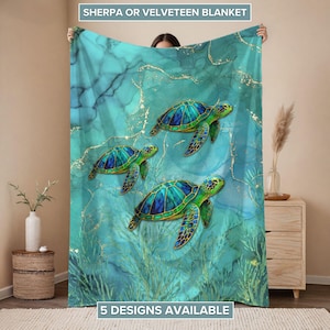 May include: A teal Sherpa or Velveteen blanket featuring three sea turtles with blue and green shells. The blanket has a marble-like background with gold accents and the text "5 DESIGNS AVAILABLE".