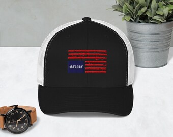 Könnte beinhalten: Eine schwarze und weiße Trucker-Kappe mit einem roten, weißen und blauen, abgenutzten amerikanischen Flaggen-Design. Die Flagge trägt den Schriftzug "MAYDAY".