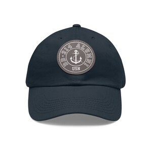 Puede incluir: Una gorra de béisbol azul marino con un parche gris que presenta un ancla blanca y el texto "DD-214 ALUMNI USN".