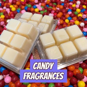 May include: Wax melt cubes in clear plastic packaging, with the text "CANDY FRAGRANCES" on a purple and blue banner. The cubes are light yellow and sit on a bed of colorful candies.