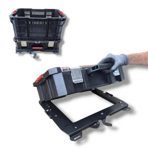 May include: A black plastic storage crate with red accents and a metal locking mechanism, shown both as a standalone unit and being lifted from a black metal mounting bracket. The crate features a slatted design and a secure padlock attachment.