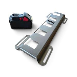 May include: A black power tool battery with a red release button positioned next to a silver metal mounting bracket featuring four rectangular cutouts and the text "B&D custom" printed on the surface with slotted mounting holes on the sides.