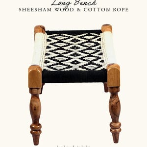 May include: A small, handcrafted bench made of sheesham wood and cotton rope. The seat features a black and white geometric pattern. The legs are turned wood, and the bench is labeled "Long Bench" and "hand made in India."