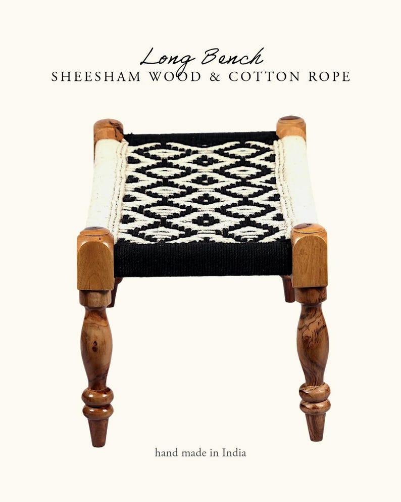May include: A small, handcrafted bench made of sheesham wood and cotton rope. The seat features a black and white geometric pattern. The legs are turned wood, and the bench is labeled "Long Bench" and "hand made in India."