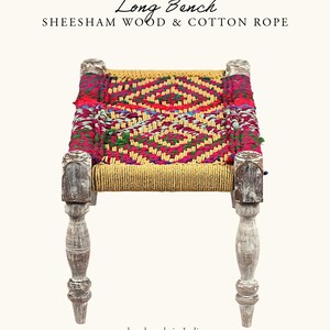 May include: A long bench made of sheesham wood and cotton rope. The seat features a vibrant, geometric pattern in red, pink, yellow, and green. The legs are painted white with a distressed finish. The text "Long Bench" and "hand made in India" are visible.