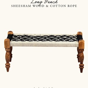 May include: A handcrafted long bench made of sheesham wood and cotton rope. The bench features a woven seat with black and white patterns, supported by four turned wooden legs. The text "Long Bench" and "hand made in India" are visible.
