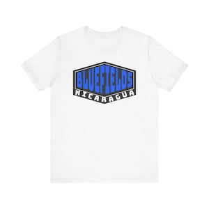 Puede incluir: Camiseta blanca con un gráfico azul y negro de un escudo con el texto "BLUEFIELDS NICARAGUA" en su interior.