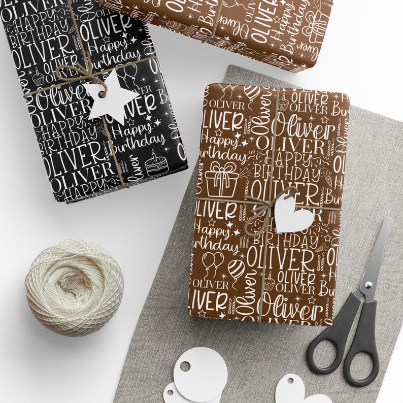 May include: Gift-wrapped presents with the name "Oliver" and "Happy Birthday" in white on black and brown wrapping paper. The gifts are tied with twine and adorned with star and heart-shaped tags. A ball of twine, scissors, and tags are also visible.