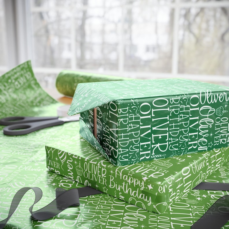 May include: Green gift boxes wrapped in matching paper with the name "Oliver" and "Happy Birthday" printed in white. A pair of scissors, ribbon, and wrapping paper are also visible.