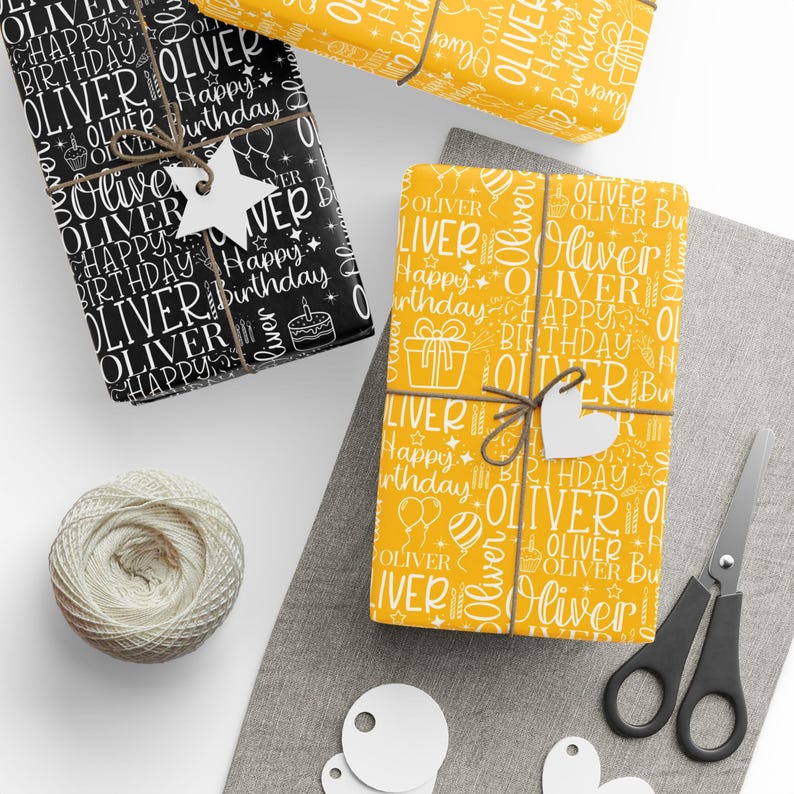 May include: Gift-wrapped presents with personalized "Oliver" birthday wrapping paper in black and yellow. The gifts are tied with twine and adorned with star and heart-shaped tags. A spool of twine, scissors, and blank tags are also visible.