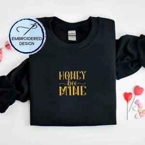 May include: Black sweatshirt with gold embroidered text that reads "Honey bee mine".