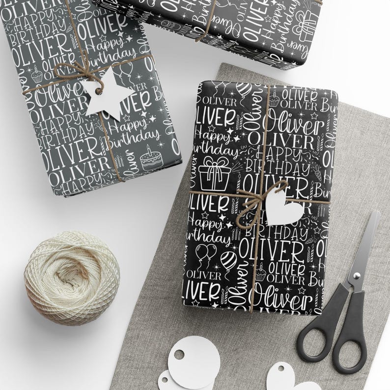 May include: Three wrapped gifts with black and white "Oliver Happy Birthday" patterned paper. Each gift is tied with twine and a white tag. A ball of twine, scissors, and blank tags are also present.