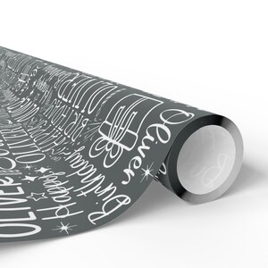 May include: Rolled gray wrapping paper with white text and illustrations. The design includes the name "Oliver", the words "Happy Birthday", and gift box illustrations. The paper is suitable for wrapping birthday gifts.