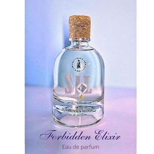 May include: A clear glass bottle of perfume with a cork stopper. The bottle has a label that says "Forbidden Elixir" and "Eau de parfum".