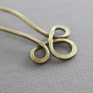 May include: A brass hair pin with a decorative knot design. The pin is a simple, elegant design that would be perfect for holding back hair.