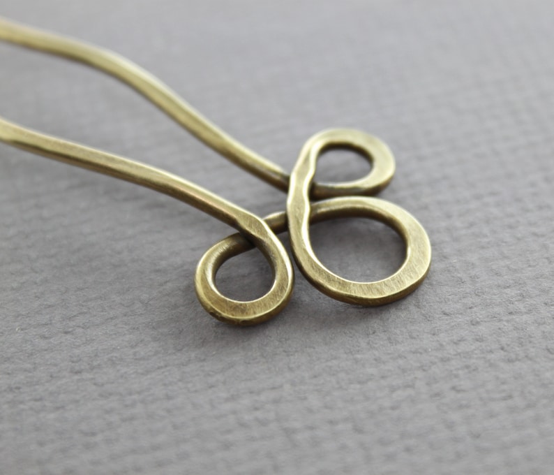 May include: A brass hair pin with a decorative knot design. The pin is a simple, elegant design that would be perfect for holding back hair.