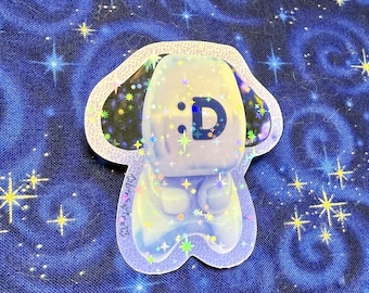 May include: A holographic sticker of a white dog with a black nose and ears. The dog has a blue and green glitter design and the text ':D' on its chest.