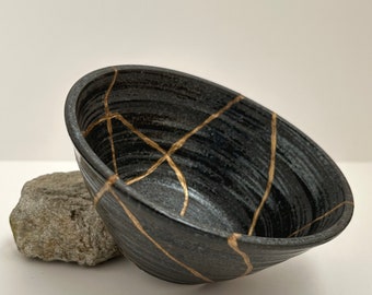 Bol Kintsugi noir style Wabi. Céramique japonaise cassée élégamment restaurée avec technique artistique. Idéal comme cadeau spécial.