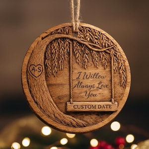 May include: A round, wooden ornament with a tree and swing design. The text "I Willow Always Love You" and "Custom Date" are engraved on the ornament. A heart with the initials "A+S" is carved into the tree. The ornament hangs from a twine string.