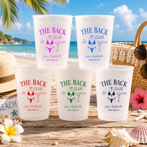 May include: Five clear plastic cups with the text "THE BACK CLUB" in various colours, including pink, blue, red, green, and navy. Each cup features a bikini graphic, a martini glass, and the text "Luna's Bachelorette, New York, NY, 2026".