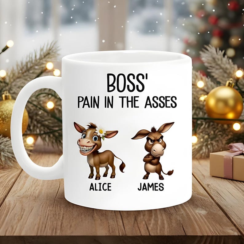 May include: White ceramic mug with the text "BOSS' PAIN IN THE ASSES". Features cartoon donkeys named Alice and James. The Alice donkey is smiling with a flower, and James is frowning with crossed arms.