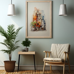 May include: A framed watercolor print of a colorful cityscape hangs on a light green wall. The artwork features buildings in shades of orange, blue, and white. A wooden chair, a small table with plants, and a potted palm tree are in the foreground.
