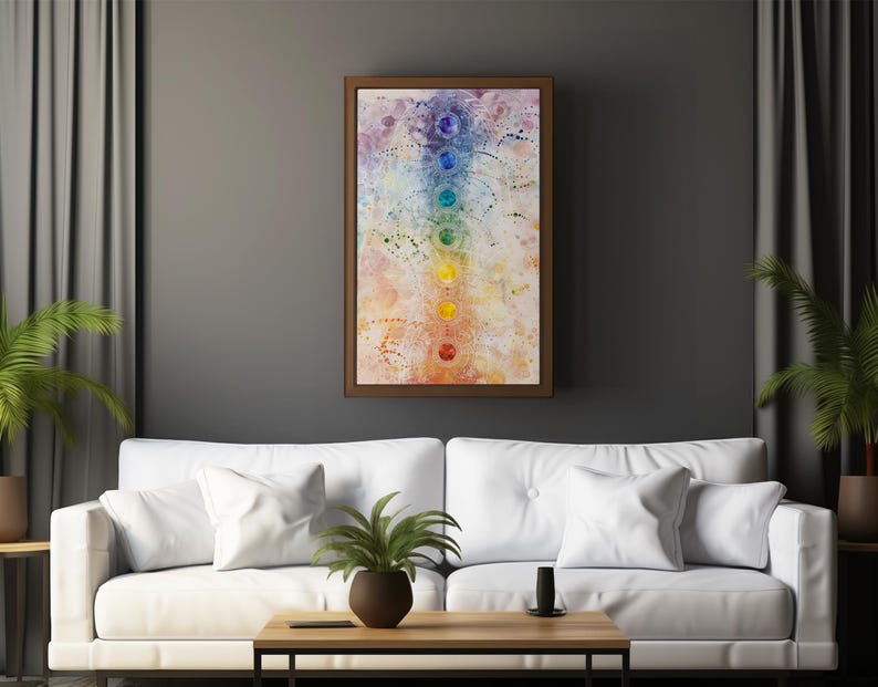 May include: A white couch with white pillows in a living room setting. A framed painting of a colorful chakra symbol hangs on the wall above the couch. A small potted plant sits on the coffee table in front of the couch.
