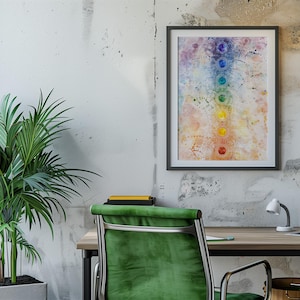 May include: A framed watercolor painting of a chakra chart with seven colored circles representing the seven chakras. The painting is hanging on a white wall with a green plant in a white pot in the foreground.