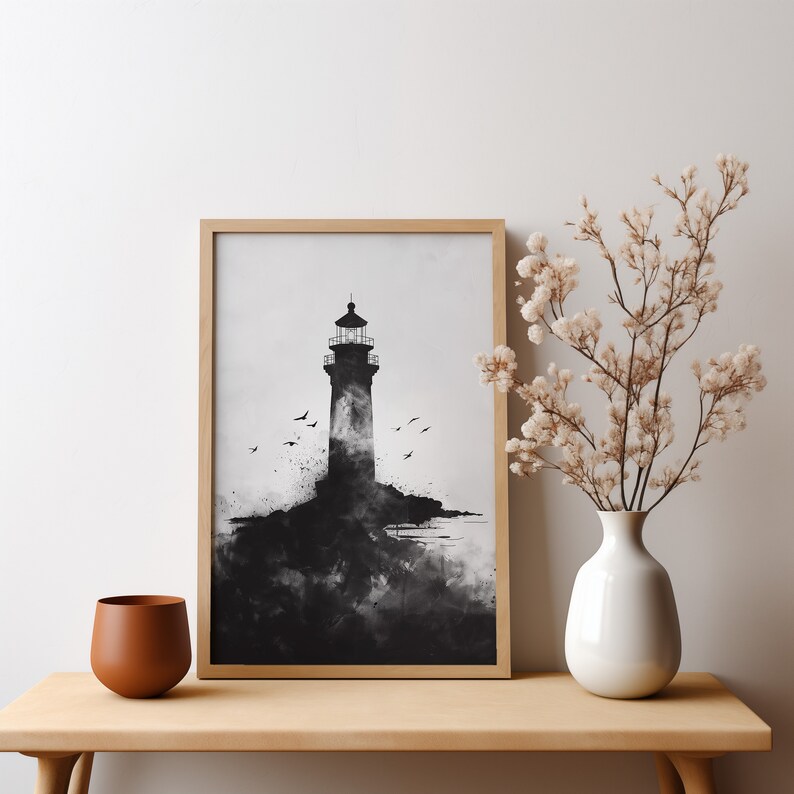 Puede incluir: Ilustraci&oacute;n en blanco y negro de un faro en una costa rocosa con p&aacute;jaros volando por encima. La imagen est&aacute; enmarcada en un marco de madera claro y se muestra en una mesa de madera.