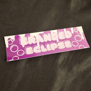 May include: Purple and white sticker with the text "Branded Eclipse" in a dripping font with white bubbles around the text.