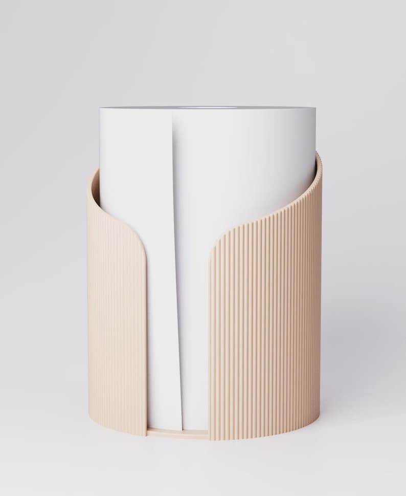 May include: A modern, minimalist paper towel holder. The holder features a cylindrical design with a light beige, ribbed exterior and a smooth, curved front. The interior holds a roll of white paper towels, creating a clean, contemporary look.