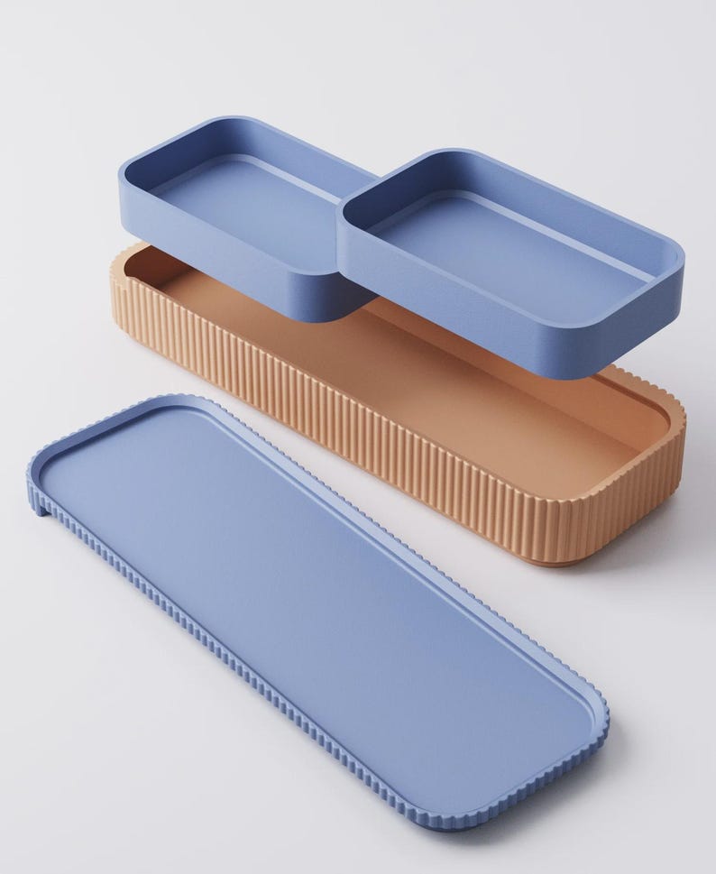 Puede incluir: Un juego de tres bandejas rectangulares en tonos azules y beige. La bandeja m&aacute;s grande es azul con un borde texturizado. La bandeja del medio es beige con estr&iacute;as verticales. Dos bandejas azules m&aacute;s peque&ntilde;as est&aacute;n apiladas encima.