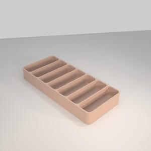 Op de afbeelding: Een rechthoekige lade-organizer van licht perzikkleurig kunststof met zes parallelle, langwerpige vakken van gelijke grootte. De lade heeft gladde, afgeronde hoeken en een stevige bodem voor het sorteren van kleine voorwerpen.