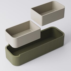Peut inclure: Ensemble de r&eacute;cipients rectangulaires vert olive et beige. Le r&eacute;cipient de base a un ext&eacute;rieur nervur&eacute;, tandis que les deux petits r&eacute;cipients sont beiges. Les r&eacute;cipients sont con&ccedil;us pour s'embo&icirc;ter.