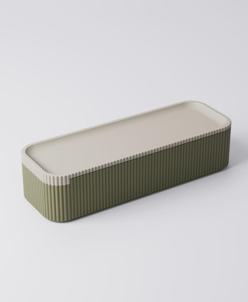 Peut inclure: Une bo&icirc;te de rangement rectangulaire avec une base vert olive c&ocirc;tel&eacute;e et un couvercle beige clair. Le couvercle a une surface lisse et un bord l&eacute;g&egrave;rement sur&eacute;lev&eacute;. La bo&icirc;te est con&ccedil;ue avec une esth&eacute;tique moderne et un style minimaliste.