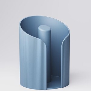 May include: A light blue paper towel holder with a vertical, ridged design on the exterior. The holder has a cylindrical center post and a curved top, creating a modern, minimalist aesthetic.