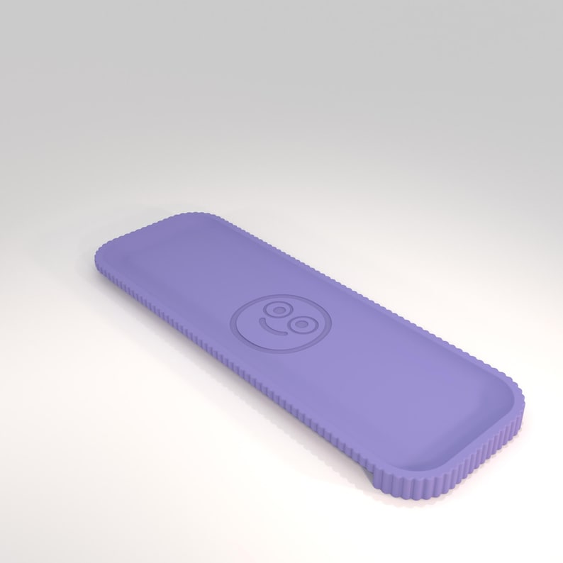 Puede incluir: Una funda rectangular para tel&eacute;fono de color lavanda con un borde acanalado y un icono de cara sonriente. La funda tiene un dise&ntilde;o ligeramente curvado y est&aacute; hecha de un material liso. La funda est&aacute; dise&ntilde;ada para proteger un tel&eacute;fono.